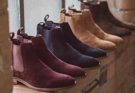 A window sill in a brick industrial building with 4 pairs of London Brogue Hamilton in Suede boots in bordo, navy, tan and dark brown