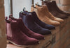 A window sill in a brick industrial building with 4 pairs of London Brogue Hamilton in Suede boots in bordo, navy, tan and dark brown