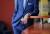 Man in a smart blue suit leaning against a table