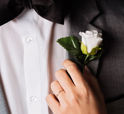 A females hand adjust the boutonnière on a Grooms jacket