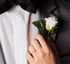 A females hand adjust the boutonnière on a Grooms jacket
