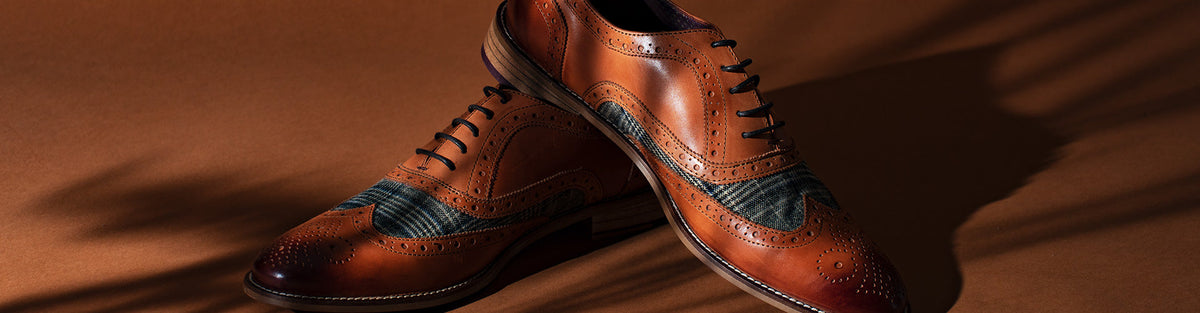 Chestnut leather brogues with tweed panels displayed on brown fabric