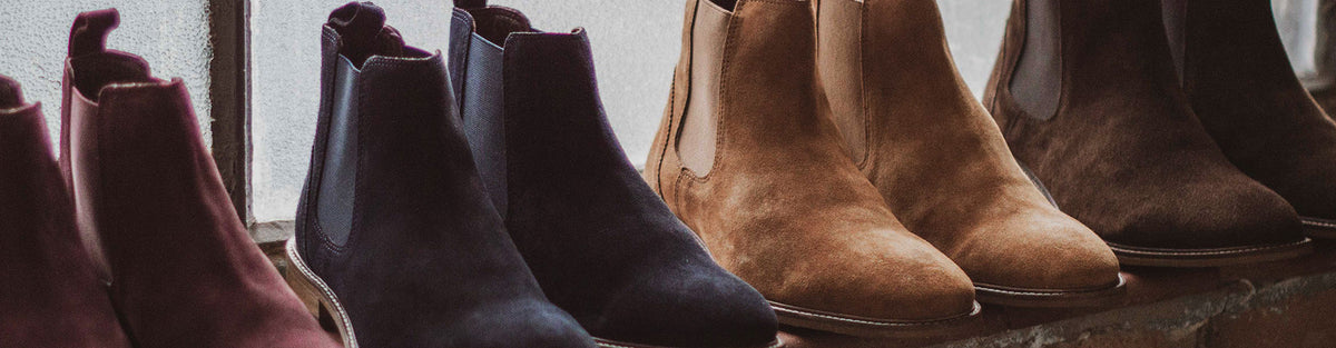 Row of suede Chelsea boots in bordo, navy, tan and brown