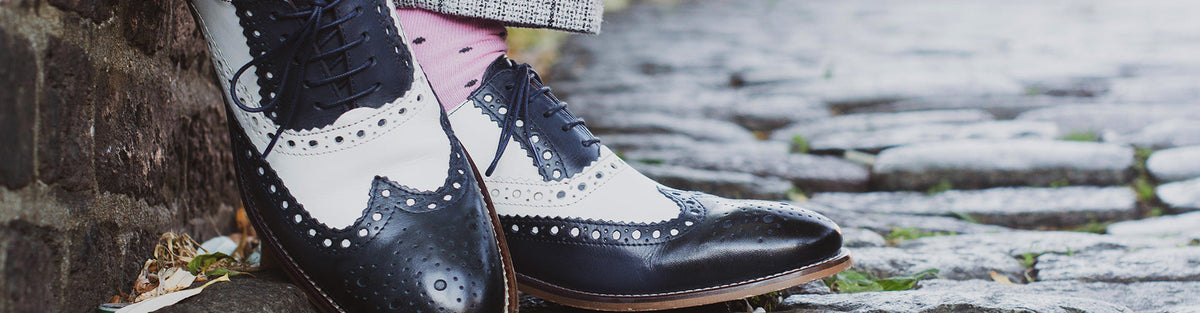 Navy and white two tone spectator brogues worn on a cobbled street